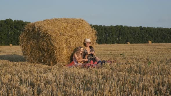 Woman with Little Daughter Relaxing Near Hay Bale