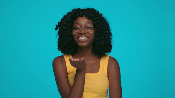 Positive Afican Woman in Eyeglasses Blowing Air Kiss