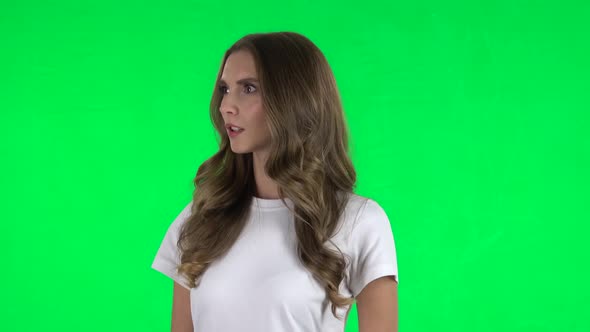 Lovable Girl Listens Attentively and Nods His Head Pointing Finger at Viewer. Green Screen
