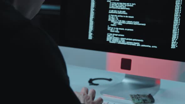 Man Coding or Hacking in Dark Office