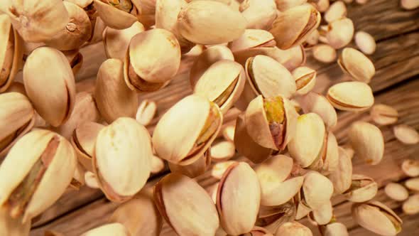 Super Slow Motion Shot of Fresh Roasted Pistachio Nuts Falling on Wooden Table at 1000 Fps