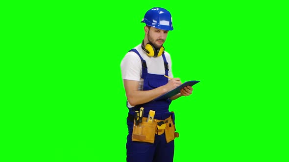 Foreman Writes Measurements on a Paper Tablet and Smiles. Green Screen