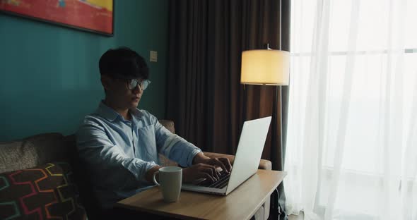 Young Attractive Asian Vietnam Man Busy Work Computer or Smart Tablet on Laptop at Home in Freelance