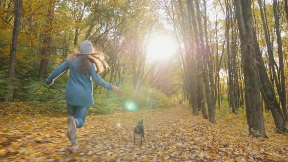 Young Girl Running with Her Cute Dog in the Autumn Forest