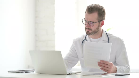 Doctor Reading Documents While Sitting in Office