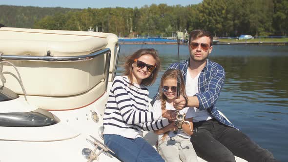 Happy Family with Daughter Fishing in Pond in Fall