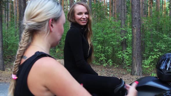 Motorbikes in the Forest Two Women Sitting on Their Motorcycles in the Middle of the Woods and