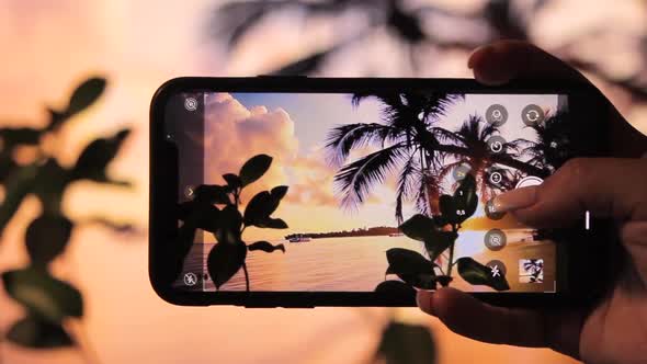 Girl photographing the sunset on the ocean