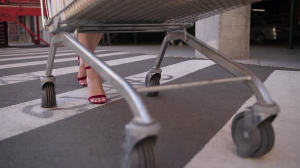 Slim Legs of Woman Carrying Shopping Cart To Car