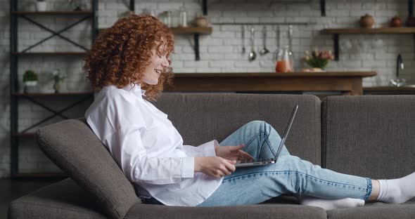 Side View of Happy Redhaired Woman with Curly Hair Talking Using Laptop Taking Via Online Virtual