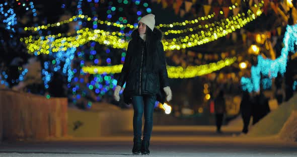 Cheerful Girl Walks on the Night Street in Winter