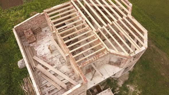 Aerial view of a brick house with wooden ceiling frame under construction