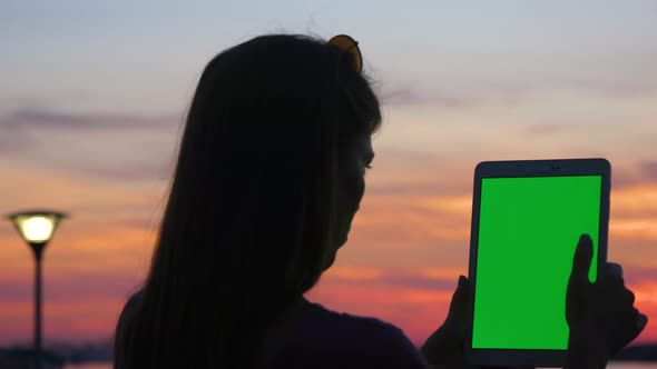 Woman Holding and Using Digital Tablet at Sunset