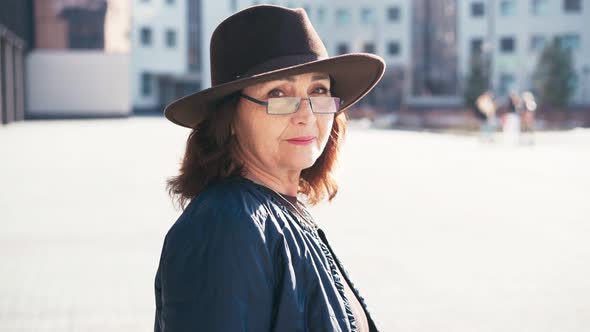 Portrait of a Senior Woman in Glasses and a Hat Looking to the Camera