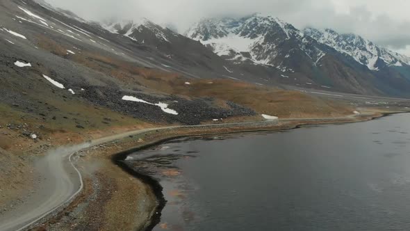 Aerial View Of SUV Driving On Gravel Road Beside Shandur Lake In Pakistan. Dolly Forward