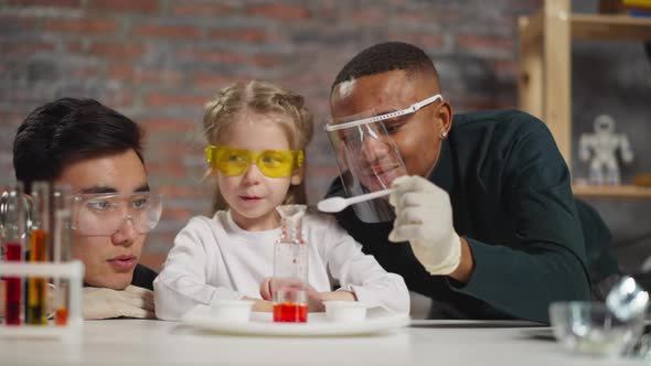 Little Girl Student Adjusts Funnel and Stirs Material in Lab