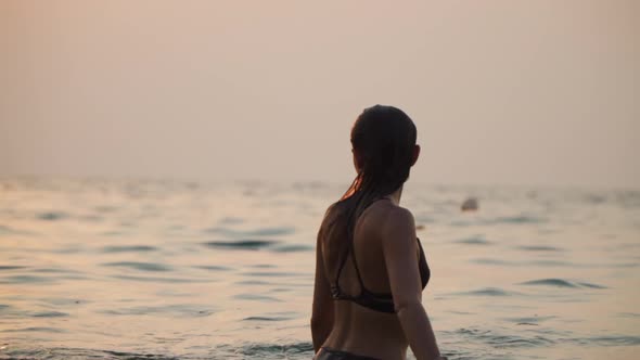 Girl Bathes in the Sea Against the Backdrop of the Sunset