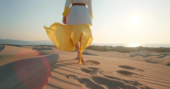 Sexy Woman in Yellow Dress Waving By Wind in Desert