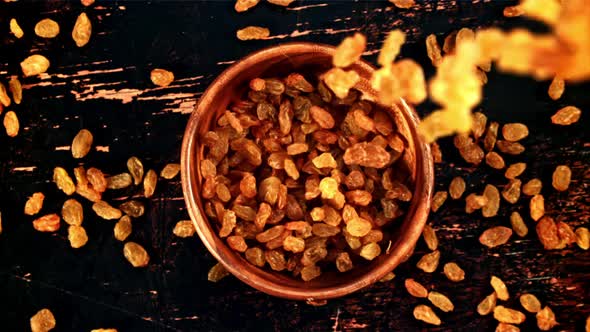 Raisins Fall Into a Wooden Bowl on the Table