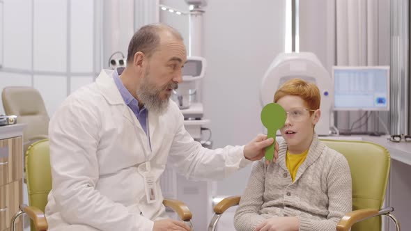 Optometrist Covering One Eye of Little Boy during Vision Test