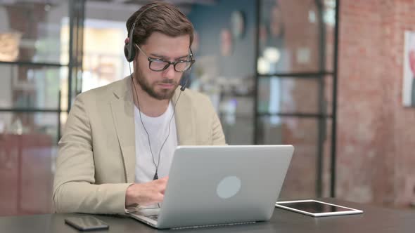 Man Wearing Headset Working on Laptop