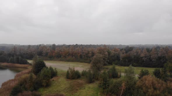 Flying over green fields and patches of forest of pine trees and leaf trees covered in autumn colors