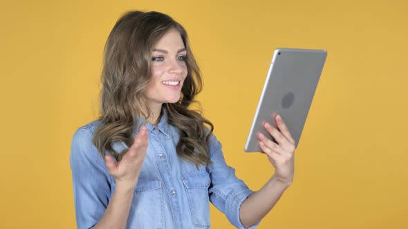 Video Chat By Young Girl Via Tablet Isolated on Yellow Background