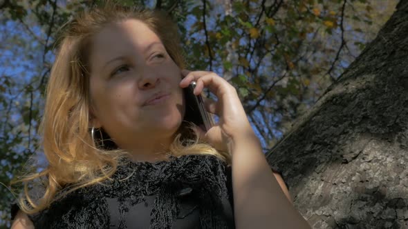 Blonde girl talking on phone in natural environment FullHD 1080p slow motion footage - Outdoor phone