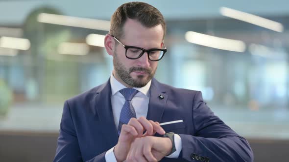 Portrait of Middle Aged Businessman Waiting and Checking Smartwatch