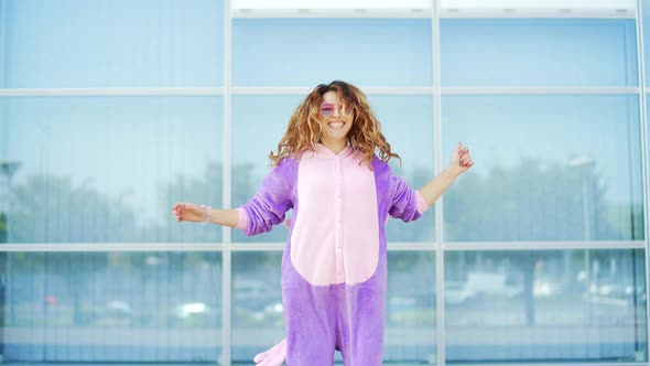 Funny cheerful happy young woman dancing outdoors on blue wall.