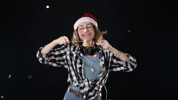 A Cute Woman in Santa Hat and Colorful Garlands and Headphones on Neck with Two Sparklers Dance at