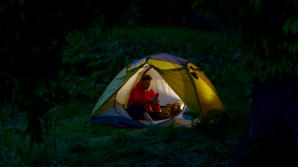 A Man in a Tent in the Night Forest