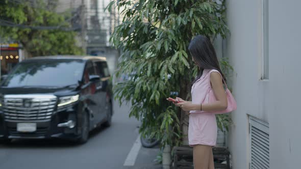 The Girl is Standing on the Street Playing a Game on Her Phone and the Camera is Zooming Towards Her