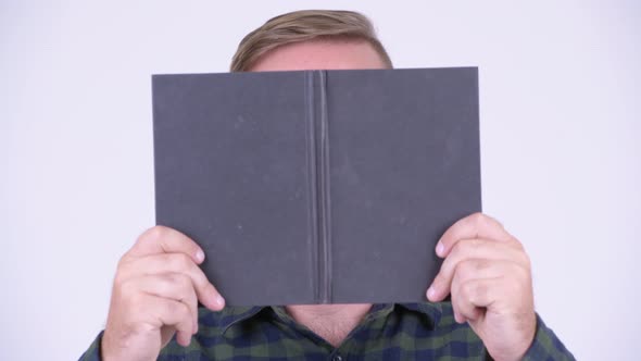 Blonde Hipster Man with Book Revealing Face and Smiling