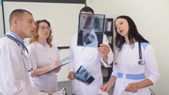 Team of Four Doctors Discusses the Results Chest X-Ray Scan of Patient inConsulting Room of Hospital