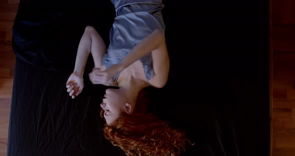 night agitation - red-haired woman lying in a bed  fidgeting in her sleep