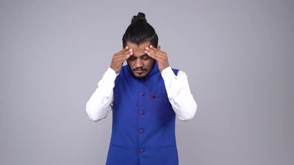 Depressed Indian man suffering from headache in an Indian outfit