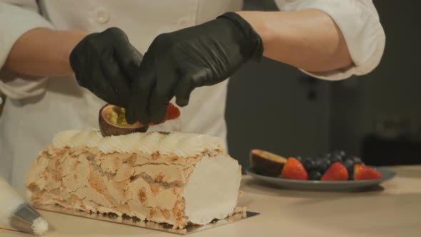 Woman Confectioner Decorates Strawberry Blueberry and Passion Fruit Dessert with Cream Meringue Roll