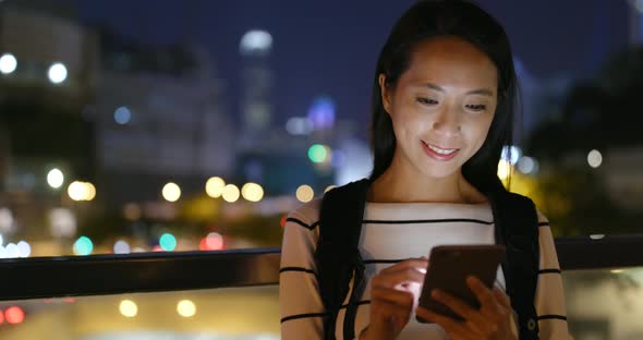 Woman use of mobile phone in city at night 