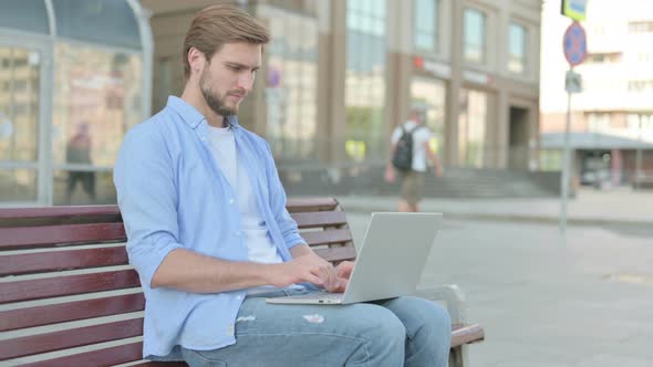 Thumbs Down By Young Man with Laptop Sitting on Bench