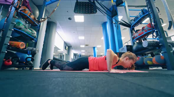 Young sportswoman doing push-ups on a mat. 