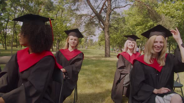 Diverse Multiethnic Graduates in Academic Dresses Listening to to Dean Speech at Graduation Day