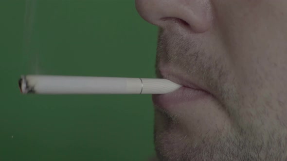 Cigarette in the Mouth of a Smoker. Close-up. Chroma Key. Green Background.