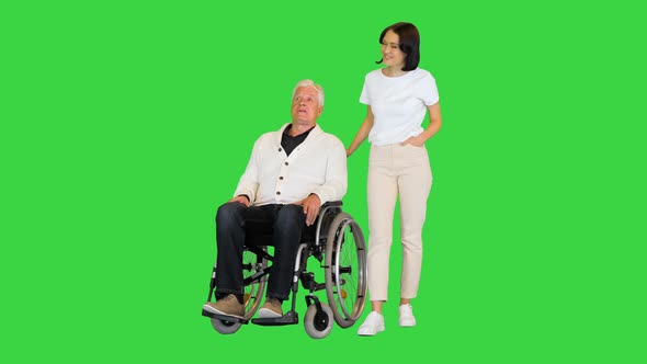 Senior Man in a Wheelchair Talking with a Young Woman on a Green Screen Chroma Key