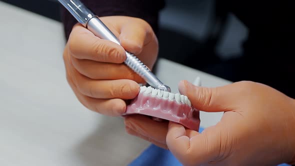 Close-up of a Dentist Practicing on a Mock-up of a Skeleton of Teeth Using a Drill Machine. the