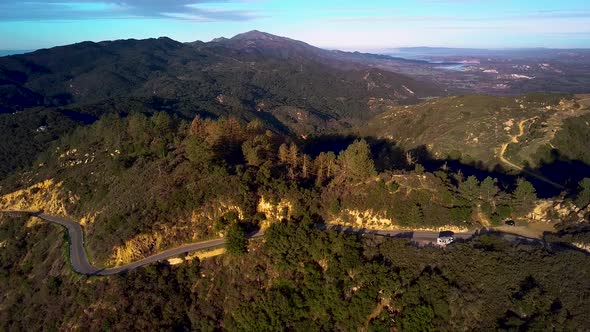 White RV parked off Winding Road in California Mountains at Dawn, Drone