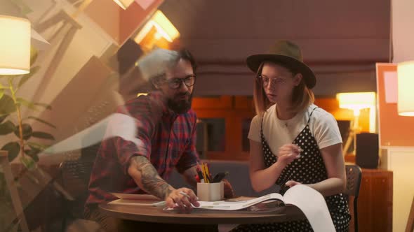 Two Stylish Diverse People Are Sitting At The Table While Energetically Discussing the Project