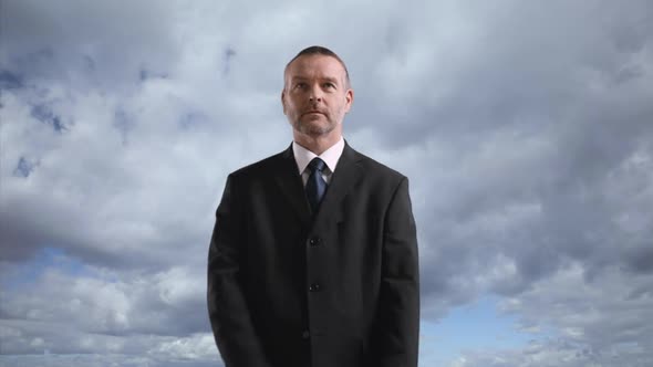 Businessman with crossed arms against cloudy sky, portrait