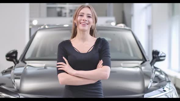 Portrait of Smiling Caucasian Girl Posing in Front of New Black Automobile