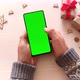 Man holding smartphone with green screen and touch on screen on Christmas background with gifts. - VideoHive Item for Sale